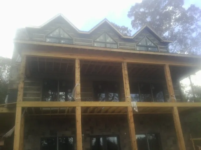 Dormers and porch framing on a large log home under construction — Roof Coating work by our crew in Sunfield