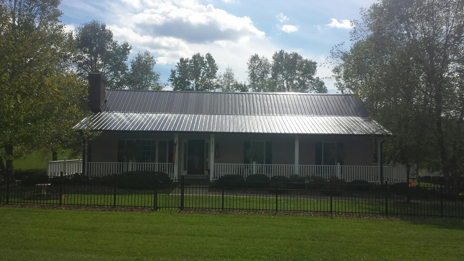 Gray metal roof on a brick ranch with a full width front porch — Gutter Guard Installation work by our crew in Sunfield